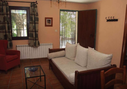 Interior de una casa que cuenta con un sofá, una mesa de café. Se ve en la imagen un radiador bajo una ventana.