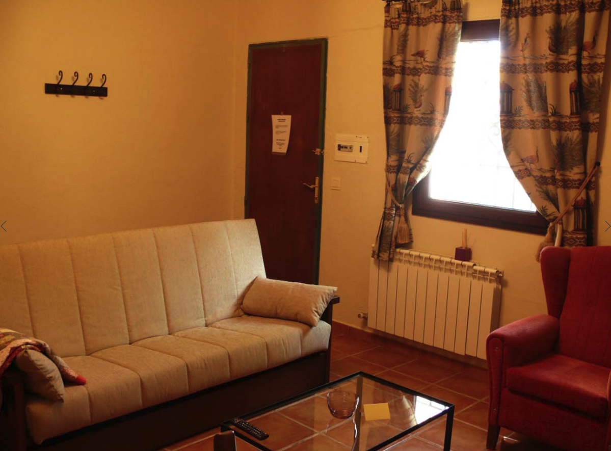 Interior de una casa que cuenta con un sofá, una mesa de café. Se ve en la imagen un radiador bajo una ventana.