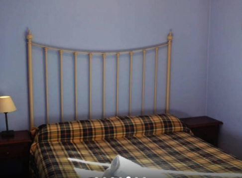 Interior de una casa que cuenta con un sofá, una mesa de café. Se ve en la imagen un radiador bajo una ventana.